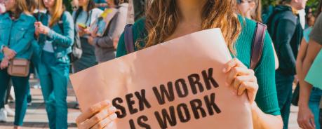 Sex work Eine Frau hält ein Schild hoch auf dem "Sex work is work" steht.