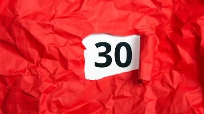 Rotes Geschenkpapier aufgerissen, darunter die Zahl 30